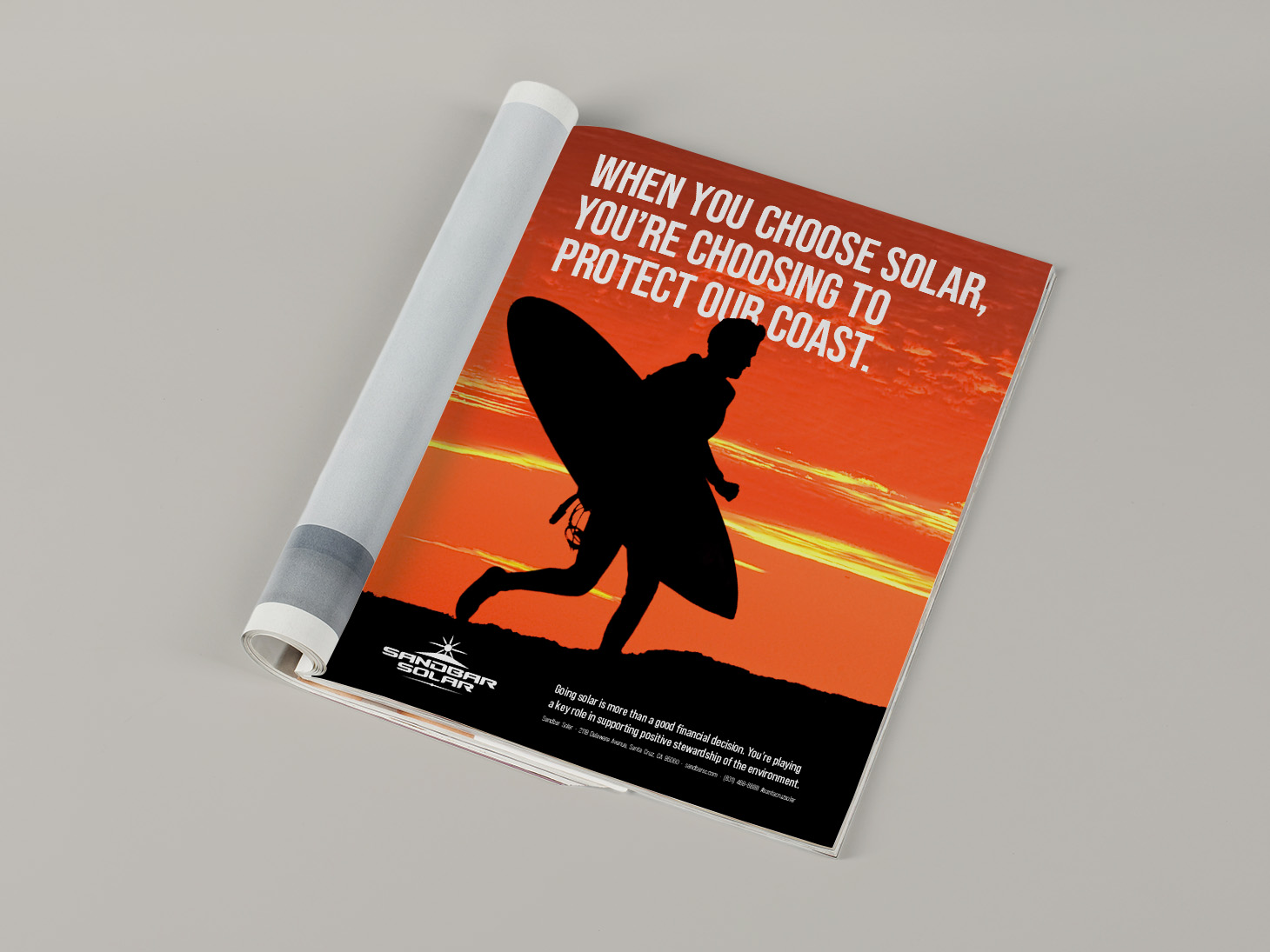 Print advertisement for Sandbar Solar featuring surfer silhouette at sunset with environmental message.